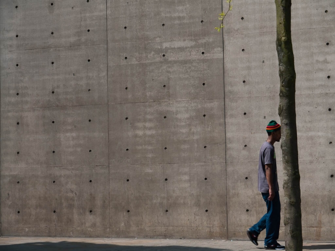 A man passes by in front of a wall at Piccadilly Gardens, Manchester.