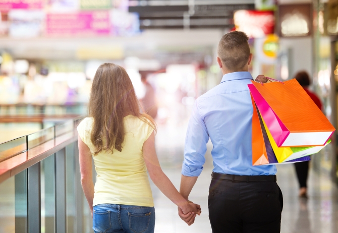 Happy young couple with bags in shopping mall