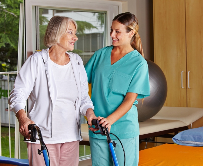 Physiotherapist helping senior woman with walker at remedial gymnastics
