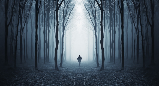 Dark spooky forest with silhouette of a man walking