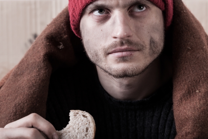 Homeless and hungry man eating a piece of bread