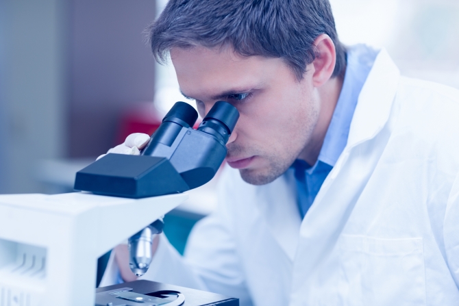 Close-up of a male scientific researcher using microscope in the laboratory
