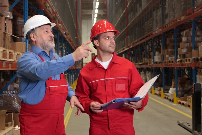 two workers in uniforms in warehouse counting stocks