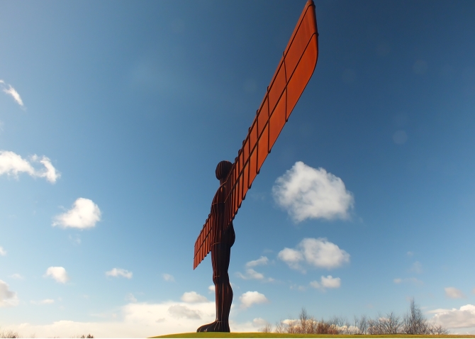 Angel of the North in bright sunlight with wings of red and dark body