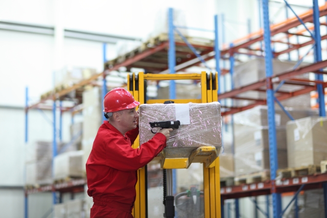 Worker with bar code reader working in warehouse - close up